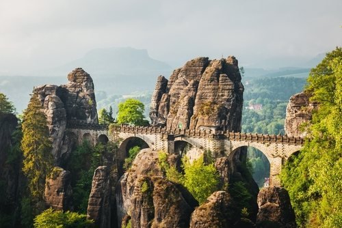 Die steinerne Basteibrücke zwischen hohen Sandsteinfelsen im Morgenlicht