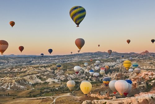 Dutzende Heißluftballons bei Sonnenaufgang über den Felsen Kappadokiens