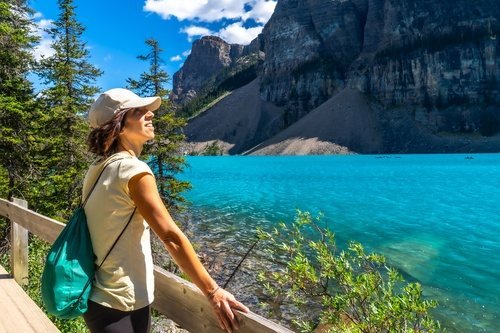 Wanderin am Ufer des türkisfarbenen Moraine Lake vor steilen Felswänden
