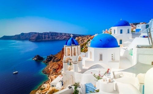 Weiße Kirche mit blauen Kuppeln über der Caldera von Santorini